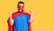 Young hispanic man wearing super hero costume screaming proud, celebrating victory and success very excited with raised arms