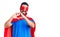 Young hispanic man wearing super hero costume smiling in love showing heart symbol and shape with hands