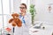 Young hispanic pediatrician woman holding teddy bear at the clinic serious face thinking about question with hand on chin,