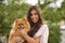 Young, Hispanic, pretty, brunette woman, wearing an elegant vintage violet dress, with a tan Pomeranian dog in her arms. Concept