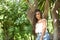 Young, Hispanic, pretty, brunette, young woman in a daisy shirt and jeans, looking at the camera calm and relaxed, leaning against