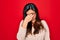 Young hispanic smart woman wearing glasses standing over red isolated background tired rubbing nose and eyes feeling fatigue and