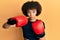 Young hispanic sporty girl using boxing gloves relaxed with serious expression on face
