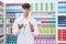 Young hispanic teenager pharmacist holding pills bottles at pharmacy