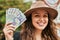 Young hispanic tourist woman smiling happy holding romania lei banknotes at the city