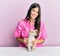 Young hispanic veterinarian girl smiling happy examining little dog at the clinic