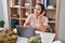 Young hispanic woman army soldier using laptop and headphones at home