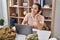 Young hispanic woman army soldier using laptop and headphones at home