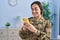 Young hispanic woman army soldier using smartphone at home