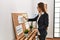 Young hispanic woman business worker writing on corkboard at office