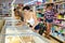 Young Hispanic woman choosing frozen convenience food in supermarket
