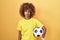 Young hispanic woman with curly hair holding football ball thinking attitude and sober expression looking self confident