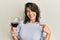 Young hispanic woman drinking a glass of red wine pointing finger to one self smiling happy and proud