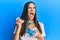 Young hispanic woman eating measure meter doing diet for weight loss angry and mad screaming frustrated and furious, shouting with