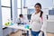 Young hispanic woman expecting a baby working at scientist laboratory with serious expression on face