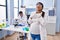 Young hispanic woman expecting a baby working at scientist laboratory smiling with hands on chest with closed eyes and grateful