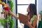 Young hispanic woman florist reading document organize shelving at florist store