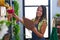 Young hispanic woman florist reading document organize shelving at florist store