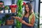 Young hispanic woman florist writing on document organize shelving at florist store