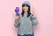 Young hispanic woman holding closed purple umbrella doing ok sign with fingers, smiling friendly gesturing excellent symbol