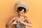 Young hispanic woman holding mexican hat smiling in love showing heart symbol and shape with hands