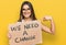 Young hispanic woman holding we need a change banner pointing finger to one self smiling happy and proud