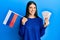 Young hispanic woman holding russia flag and rubles banknotes smiling with a happy and cool smile on face