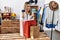 Young hispanic woman holding shopping bags and credit card at clothing store doing money gesture with hands, asking for salary