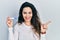 Young hispanic woman holding thermometer smiling happy pointing with hand and finger to the side