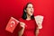 Young hispanic woman holding turkey flag and liras banknotes angry and mad screaming frustrated and furious, shouting with anger