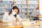 Young hispanic woman in protective mask reading books in library