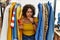 Young hispanic woman searching clothes on clothing rack using smartphone feeling unwell and coughing as symptom for cold or