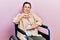 Young hispanic woman sitting on wheelchair gesturing with hands showing big and large size sign, measure symbol