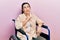 Young hispanic woman sitting on wheelchair thinking concentrated about doubt with finger on chin and looking up wondering