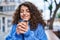 Young hispanic woman smiling confident drinking coffee at street