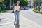 Young hispanic woman smiling confident using e-scooter at street