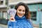 Young hispanic woman smiling happy holding sweden krone banknotes at the city