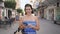 Young hispanic woman smiling happy using smartphone at the street