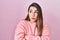 Young hispanic woman standing over pink background looking to the side with arms crossed convinced and confident