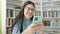 Young hispanic woman student smiling using smartphone at library university