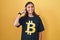 Young hispanic woman wearing bitcoin t shirt smiling pointing to head with one finger, great idea or thought, good memory