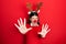Young hispanic woman wearing deer christmas hat and red nose afraid and terrified with fear expression stop gesture with hands,