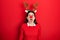 Young hispanic woman wearing deer christmas hat and red nose angry and mad screaming frustrated and furious, shouting with anger