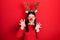 Young hispanic woman wearing deer christmas hat and red nose smiling funny doing claw gesture as cat, aggressive and sexy