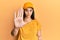 Young hispanic woman wearing delivery uniform and cap doing stop sing with palm of the hand