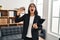 Young hispanic woman working at consultation office holding sand clock angry and mad screaming frustrated and furious, shouting