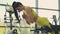 Young Hispanic woman in a yellow tracksuit performs a hyperextension exercise to train the muscles of the back. A