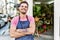 Young hispanic worker wearing apron standing with arms crossed gesture at the florist