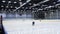 Young hockey player with stick skates along ice arena