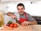 Young home cook man in apron slicing carrot with kitchen knife happy and relaxed